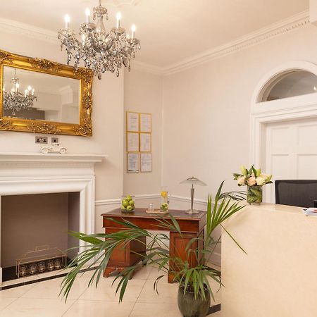 Montcalm Brewery Townhouse Londres Exterior foto The photo shows a stylish reception area. There is a decorative chandelier hanging from the ceiling, providing elegant lighting. A large, ornate mirror is mounted on the wall beside the fireplace, which features a simple, classic design. In front of 