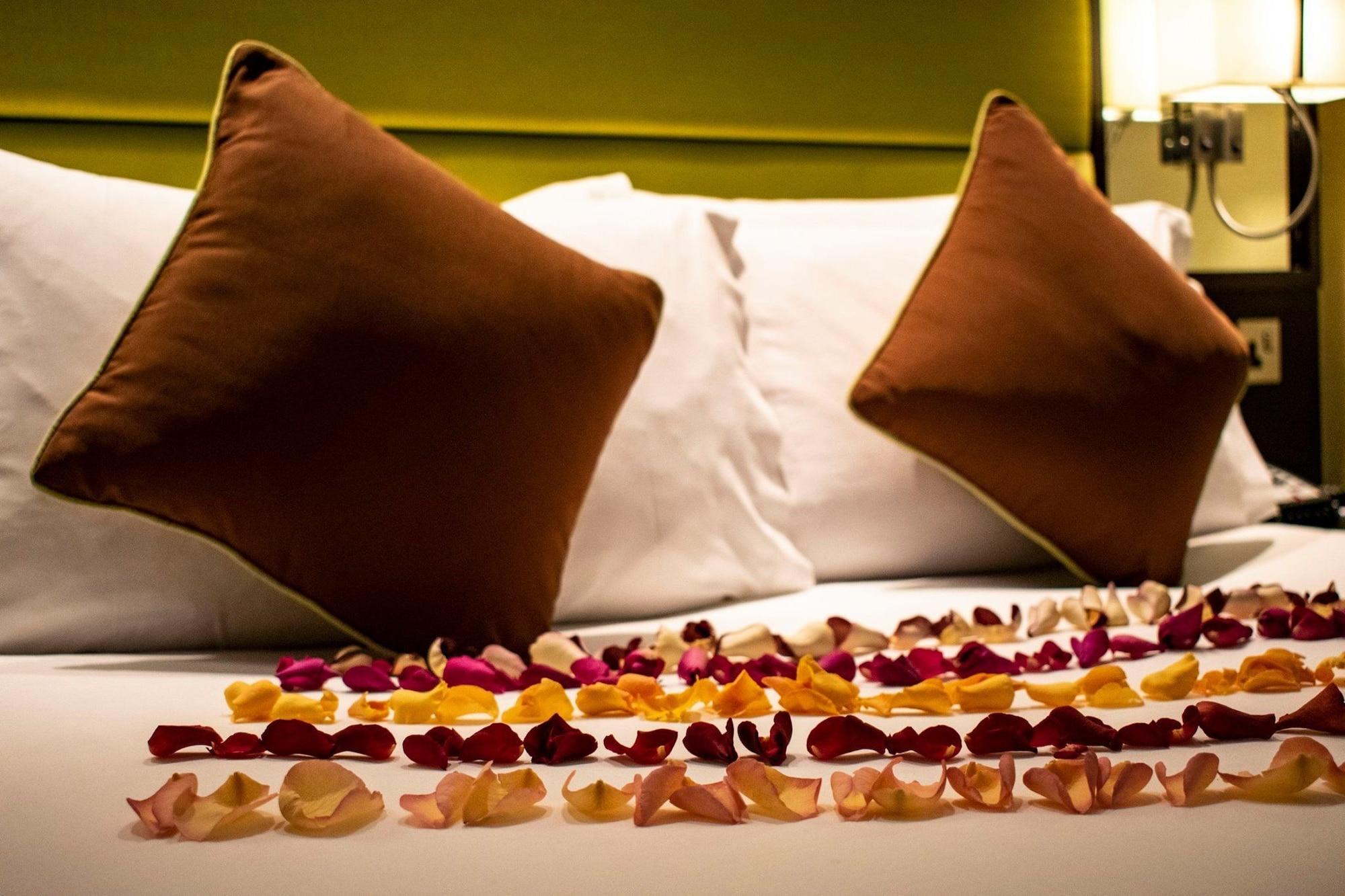 Montcalm Brewery Townhouse Londres Exterior foto The photo shows a neatly arranged bed with two white pillows and brown decorative cushions. Scattered across the bed is a decorative display of flower petals in various colors, including pink, yellow, and orange, creating a romantic or tranquil ambia