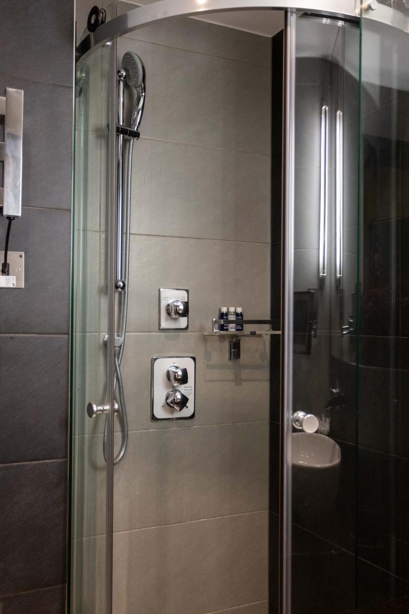 Montcalm Brewery Townhouse Londres Exterior foto The photo shows a modern shower area. It features glass panels and tiled walls in a neutral color palette, creating a sleek and contemporary look. There are two main control panels for adjusting the water temperature and pressure, with various knobs 