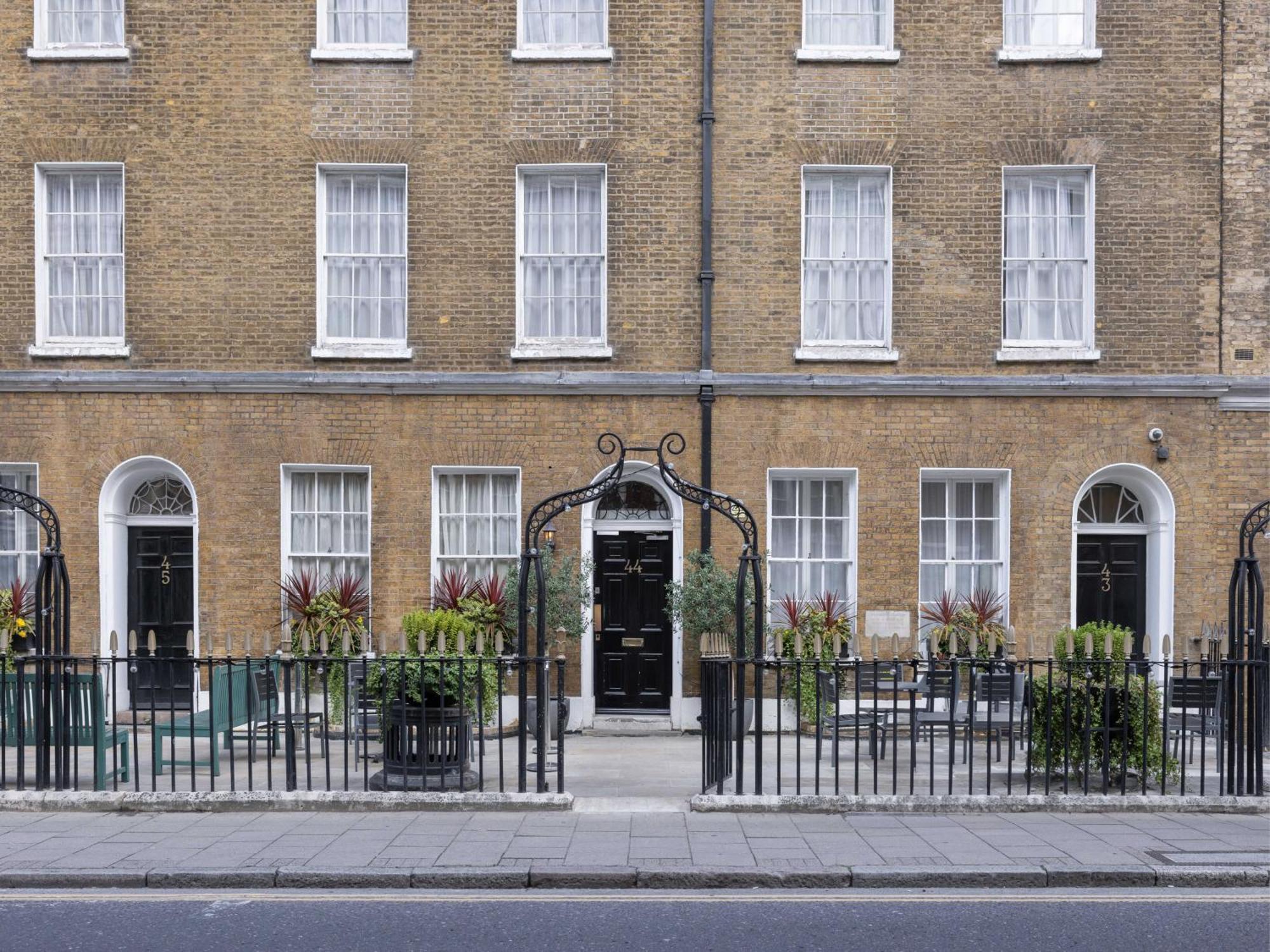 Montcalm Brewery Townhouse Londres Exterior foto The photo shows a row of three-story brick buildings, featuring a classic design with large windows and decorative ironwork. The buildings are painted in a muted yellow-brown color, typical of older urban architecture. In front of the buildings, ther