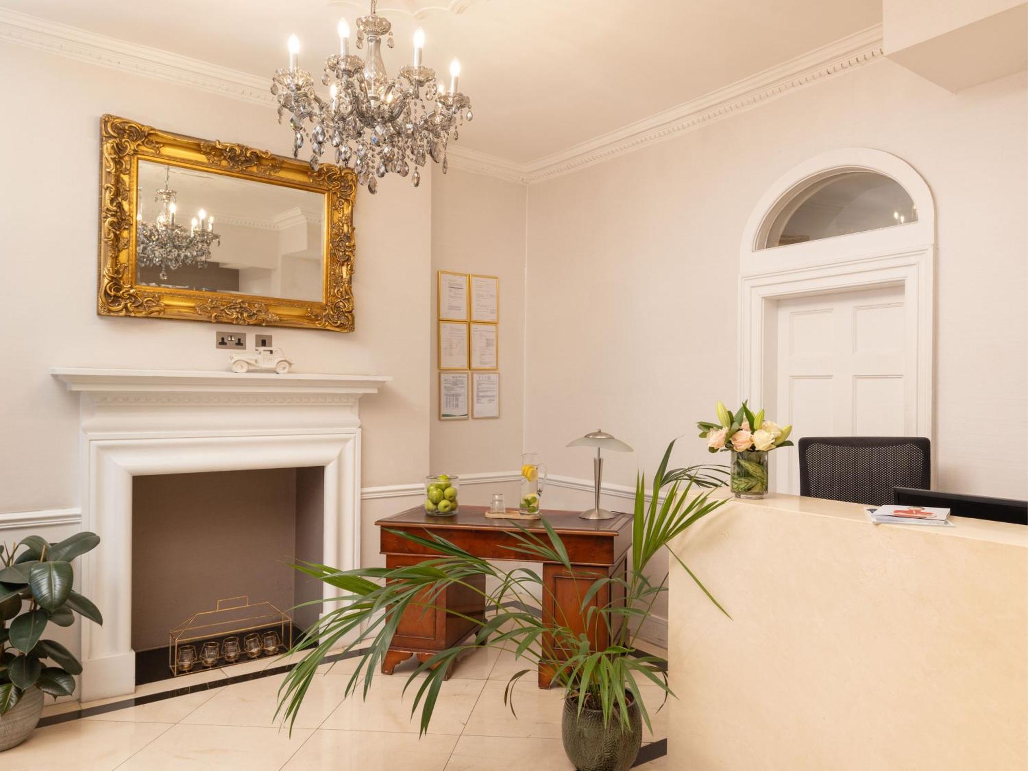 Montcalm Brewery Townhouse Londres Exterior foto The photo shows a stylish reception area. There is a decorative chandelier hanging from the ceiling, providing elegant lighting. A large, ornate mirror is mounted on the wall beside the fireplace, which features a simple, classic design. In front of 