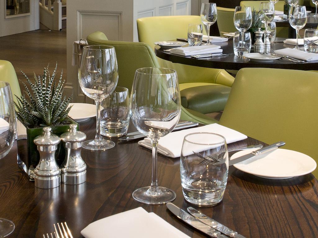 Montcalm Brewery Townhouse Londres Exterior foto The photo shows a dining setup in a restaurant. There are tables with a polished wooden surface and elegant place settings. Each setting includes multiple wine glasses and water glasses, neatly arranged with folded napkins. 

In the center, there are