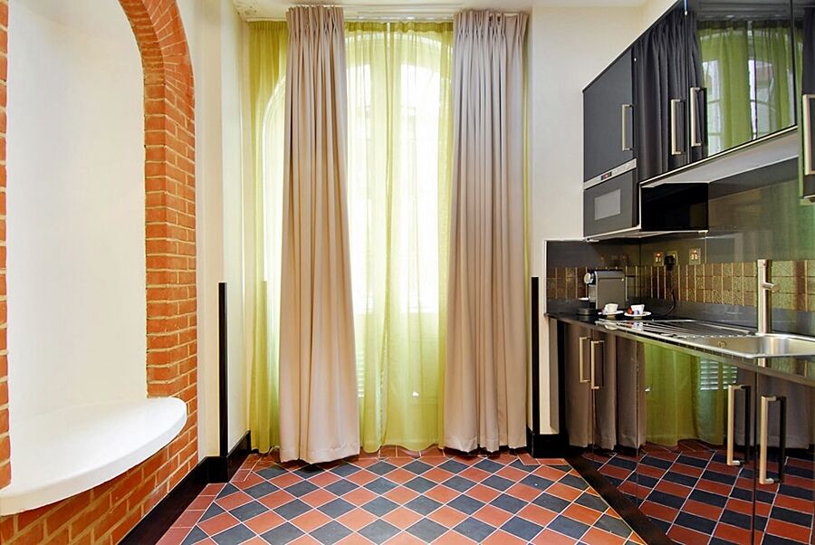 Montcalm Brewery Townhouse Londres Exterior foto The photo shows a kitchen area with modern design elements. There are large, light-colored curtains hanging from the windows, allowing natural light to filter in. The walls are partially exposed brick, giving a warm texture to the room. The flooring 