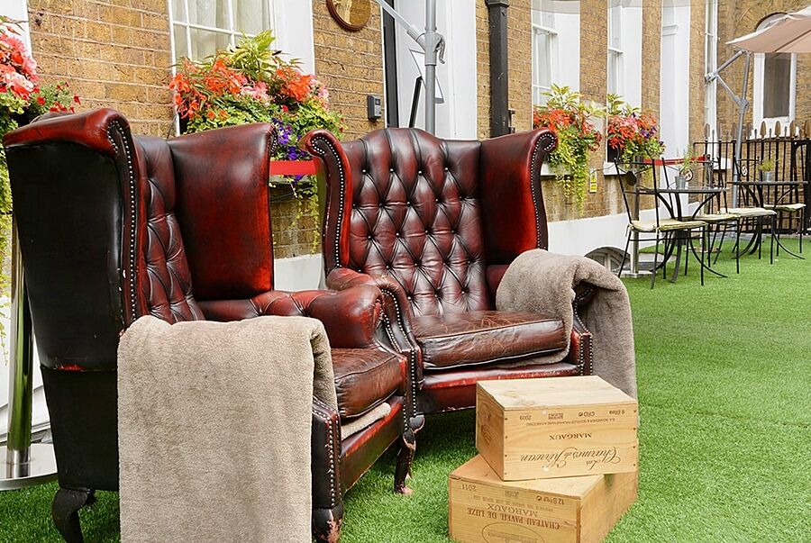 Montcalm Brewery Townhouse Londres Exterior foto The photo depicts two large, elegant armchairs with a classic design, featuring rich burgundy leather upholstery and button tufting. They are positioned in a cozy outdoor setting, with lush green artificial grass beneath them. Next to the chairs, the